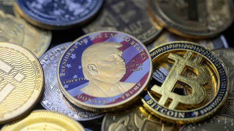 Donald Trump-themed coin placed beside Bitcoin and other cryptocurrencies, arranged for a staged photo illustration, Brussels, Belgium, August 5, 2025.