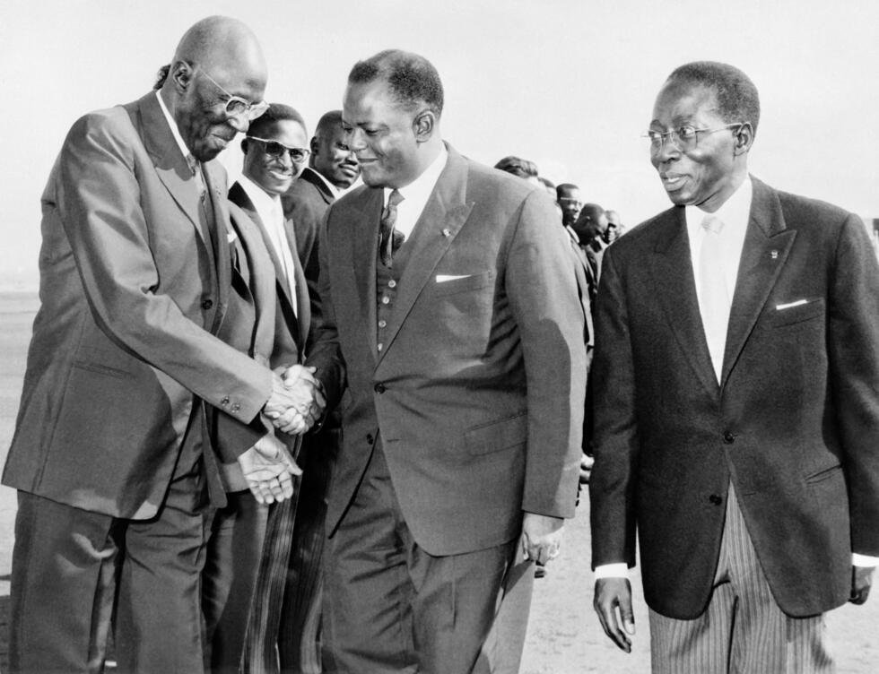 Le président béninois (ancien Dahomey) Hubert Maga (au centre) serre la main à Lamine Gueye (à gauche), président du Parlement sénégalais, sous le regard de Léopold Sédar Senghor (à droite), président sénégalais, le 6 mai 1963 lors de sa visite officielle au Sénégal.