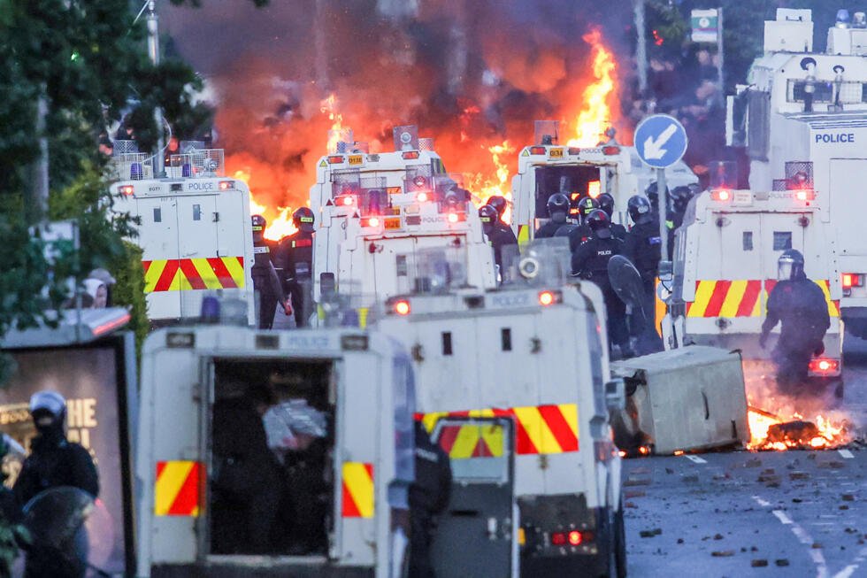 Des feux font rage autour de véhicules de police tandis que des manifestants s'affrontent avec les forces de l'ordre à Glengormley, au nord de Belfast, en Irlande du Nord, le 10 juin 2026