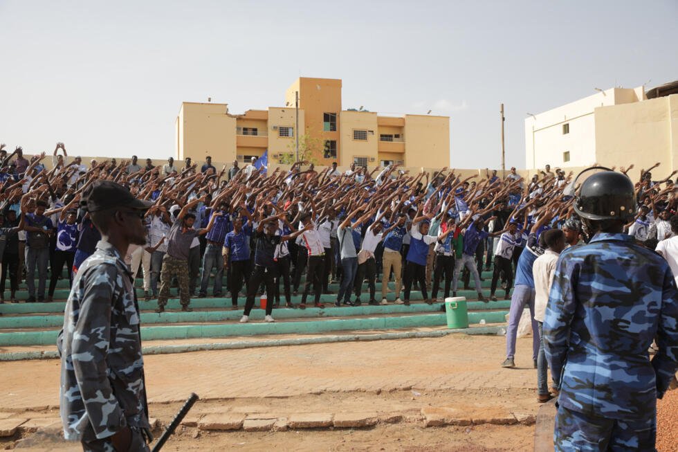 Des soldats montent la garde tandis que les supporters acclament les joueurs lors du match de football de la Premier League soudanaise opposant Al Merrikh à Al-Hilal au stade de Khartoum, au Soudan,